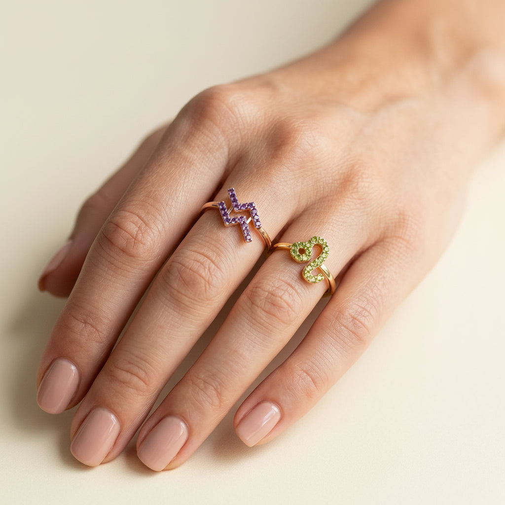 Hand wearing two colorful rings on a neutral background