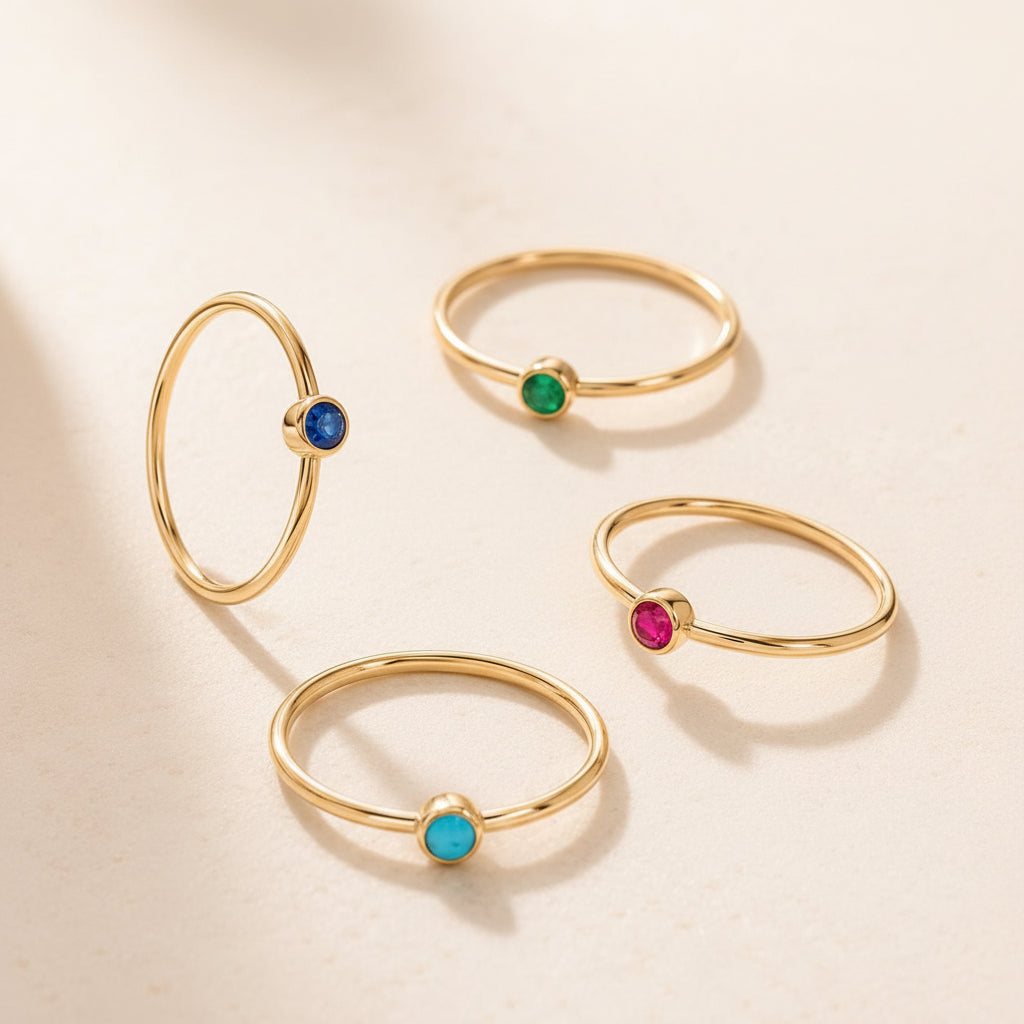 Set of gold rings with colored gemstones on a beige surface