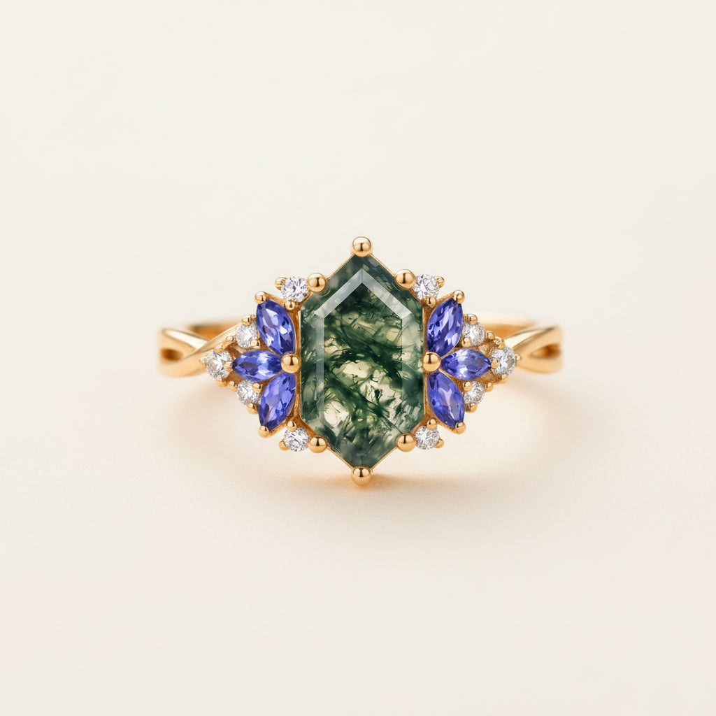 A gold ring featuring a central green marquise-cut gemstone with white inclusions, flanked by blue marquise-cut stones and small clear accent stones, resting on a textured wooden surface.