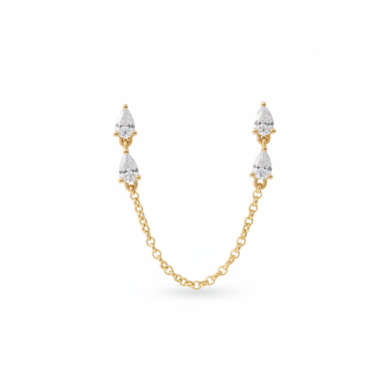 A pair of gold drop earrings with pear-cut clear stones and a connecting chain, presented in an open blue velvet jewelry box with the brand name AURORA FINE JEWELRY visible inside.