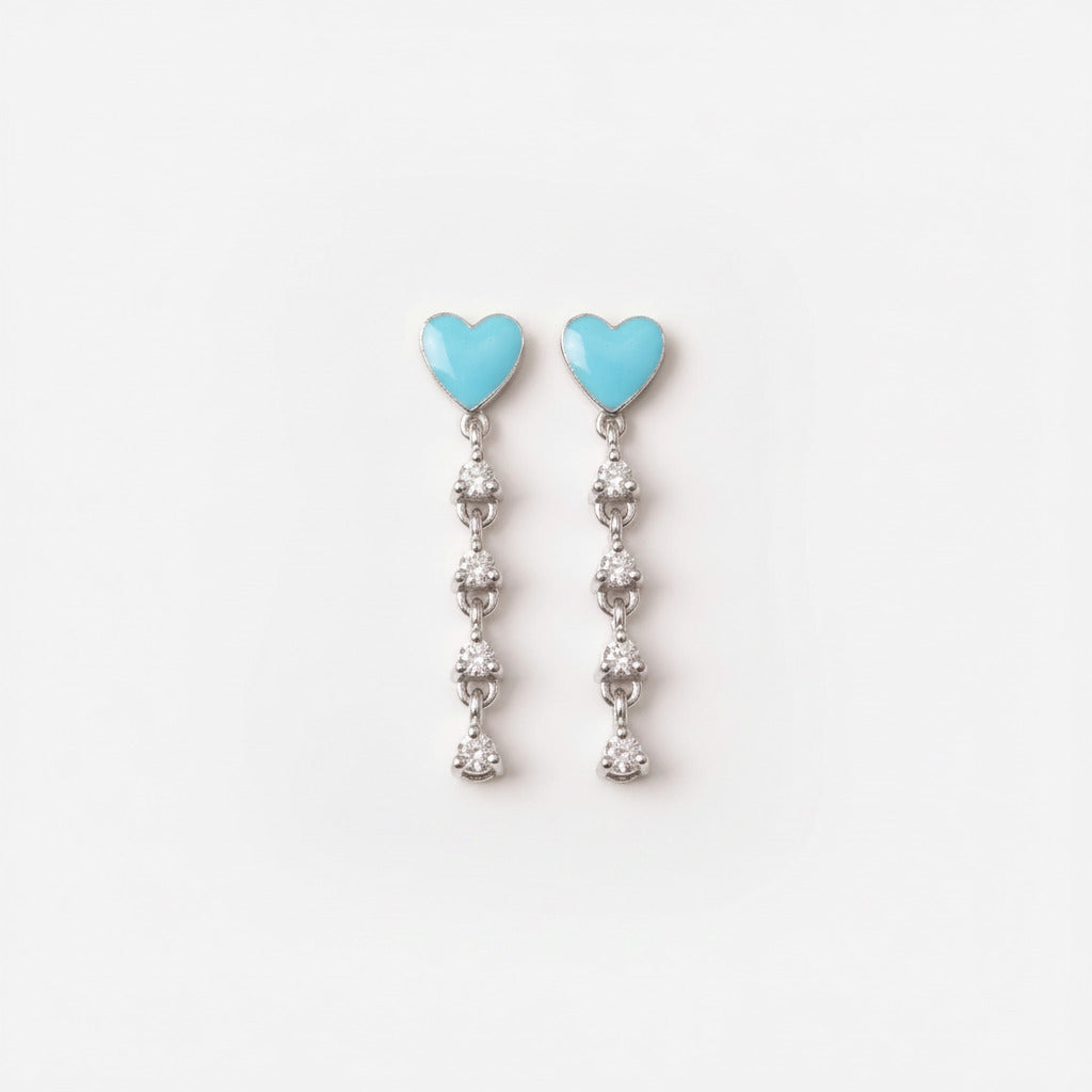 A pair of silver dangle earrings with light blue heart-shaped tops and clear rhinestone drops, displayed on a white ceramic plate.
