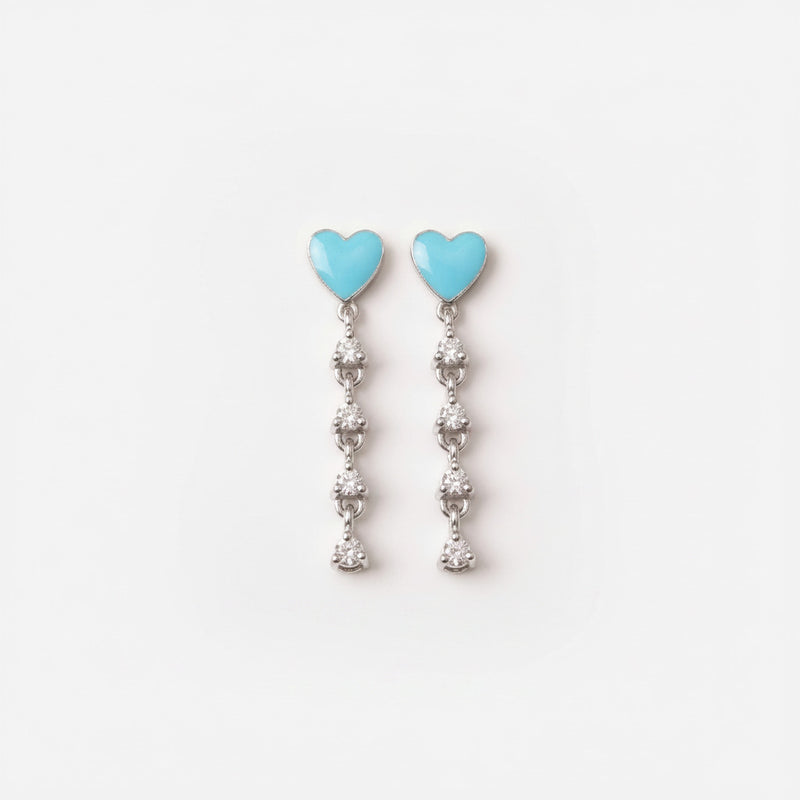 A pair of silver dangle earrings with light blue heart-shaped tops and clear rhinestone drops, displayed on a white ceramic plate.