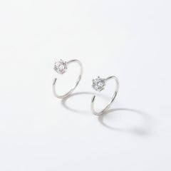A pair of silver open-hoop earrings with clear gemstones, displayed in a gray velvet jewelry box.