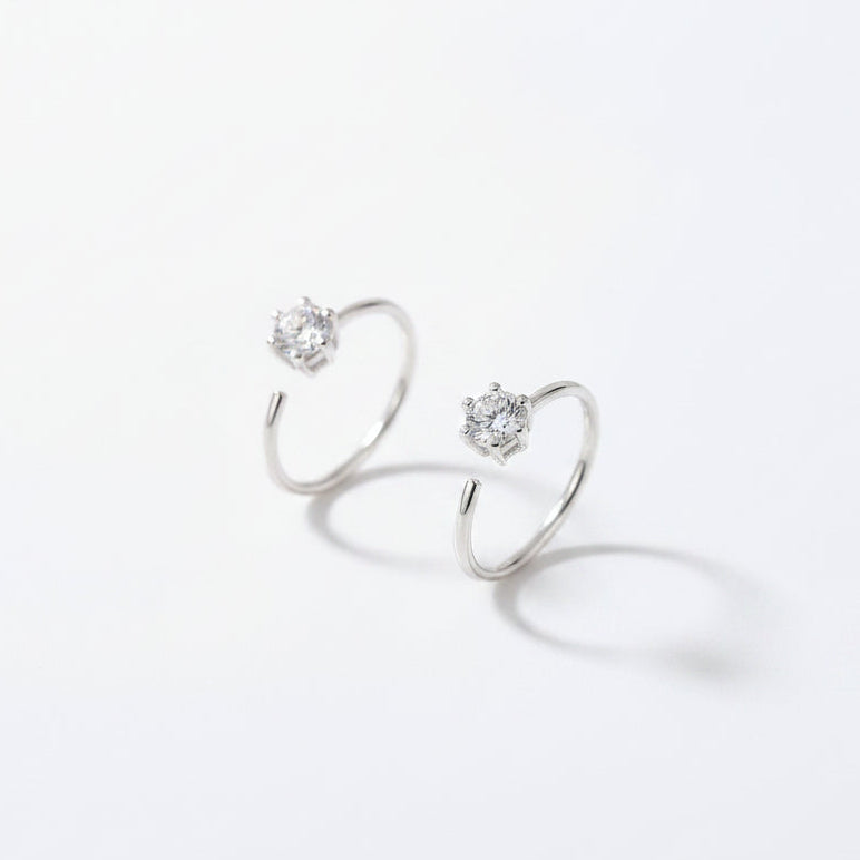 A pair of silver open-hoop earrings with clear gemstones, displayed in a gray velvet jewelry box.