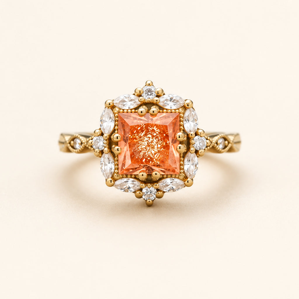 A yellow gold ring featuring a square orange center stone surrounded by clear marquise and round stones, resting on a textured stone surface with a blurred natural background.