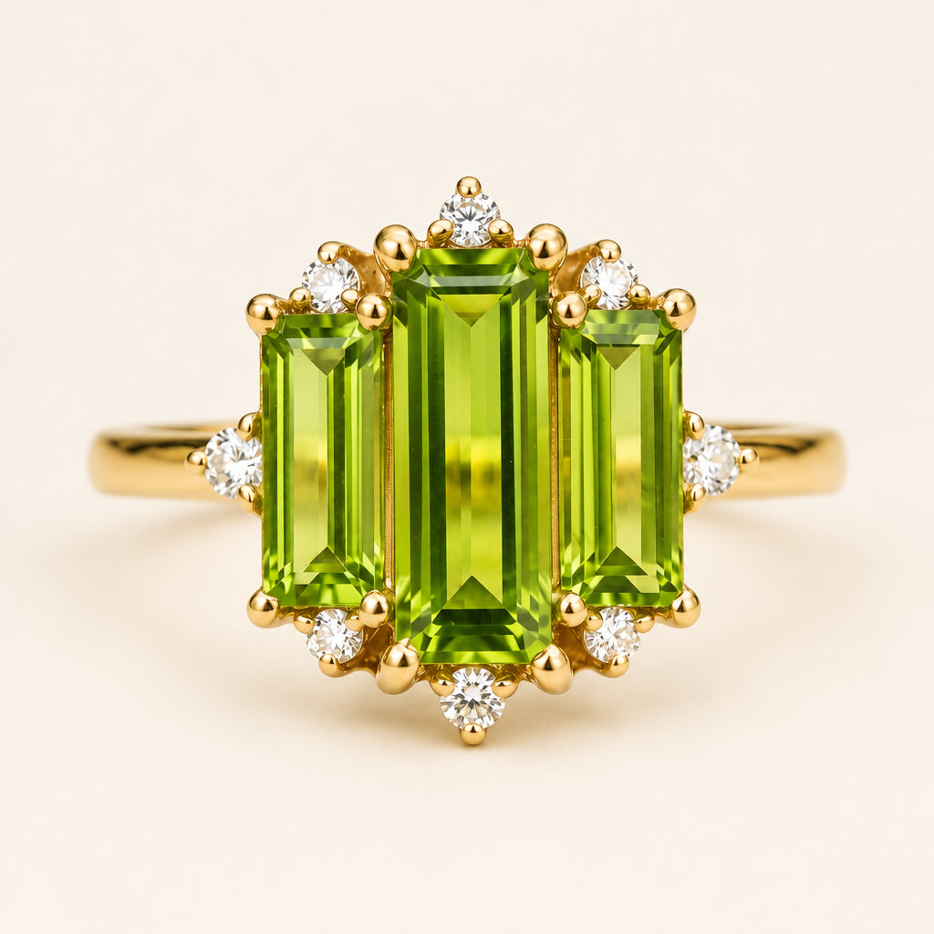 A yellow gold ring featuring a large emerald-cut green peridot center stone with smaller accent diamonds and a halo setting, displayed on a light marble surface.